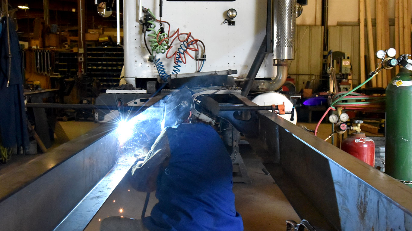 Welder working on the frame of a semi truck.